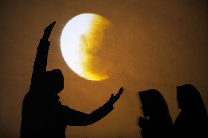 Warga berpose dengan latar gerhana bulan super blue blood moon yang ditampilkan di layar saat gerhana tersebut terlihat dari Masjid Al-Akbar, Surabaya, Jawa Timur, Rabu malam. ANTARA FOTO/Zabur Karuru
