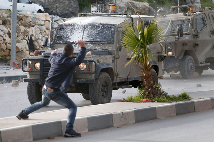 Sejumlah warga Palestina melemparkan batu ke kendaraan tentara Israel setelah pasukan memasuki desa Halhoul di Tepi Barat