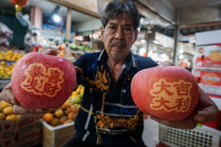 Pedagang menunjukkan buah apel fuji dengan huruf hanzi (Tiongkok) di Pasar Gede, Solo, Jawa Tengah. Apel fuji yang diimpor dari Tiongkok tersebut banyak dicari warga jelang Tahun Baru Imlek dan dijual dengan harga Rp300 ribu per kotak isi 12 apel. ANTARA/Mohammad Ayudha