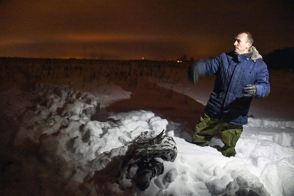 Seorang pria menunjukkan bagian dari puing-puing di lokasi kecelakaan pesawat di distrik Ramensky, di pinggiran Moskow, Minggu 11 Februari 2018 waktu setempat.