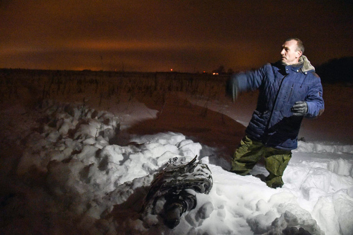 Seorang pria menunjukkan bagian dari puing-puing di lokasi kecelakaan pesawat di distrik Ramensky, di pinggiran Moskow, Minggu 11 Februari 2018 waktu setempat.