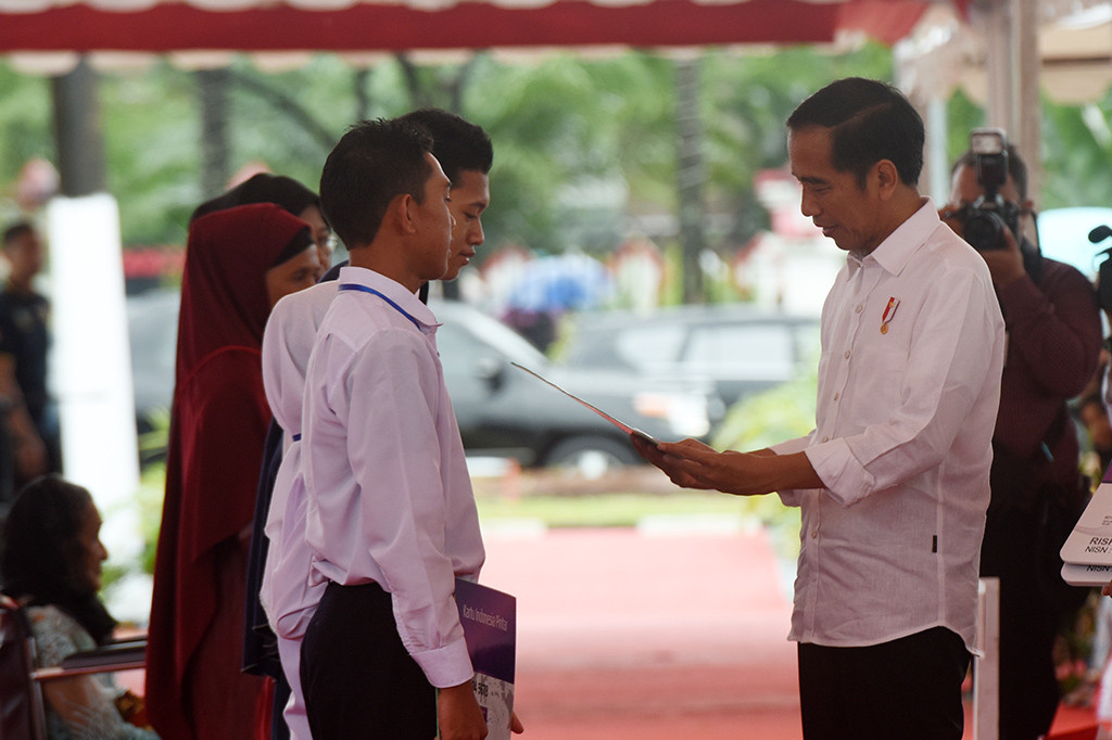 Presiden Joko Widodo menyerahkan secara simbolik Kartu Program Keluarga Harapan (PKH) dan Kartu Indonesia Pintar (KIP) di Lapangan Syech Yusuf, Kabupaten Gowa, Sulsel.
