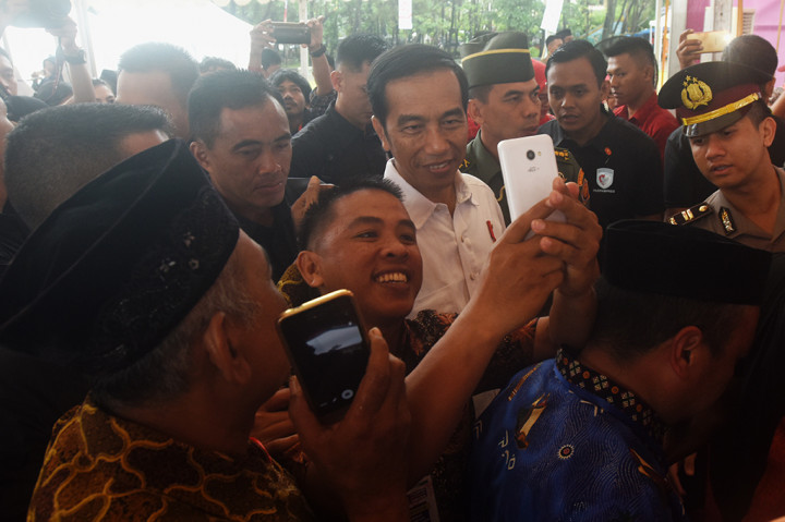 Presiden Joko Widodo berfoto bersama warga seusai penyerahan secara simbolik Kartu Program Keluarga Harapan (PKH) dan Kartu Indonesia Pintar (KIP) di Lapangan Syech Yusuf, Kabupaten Gowa, Sulawesi Selatan.