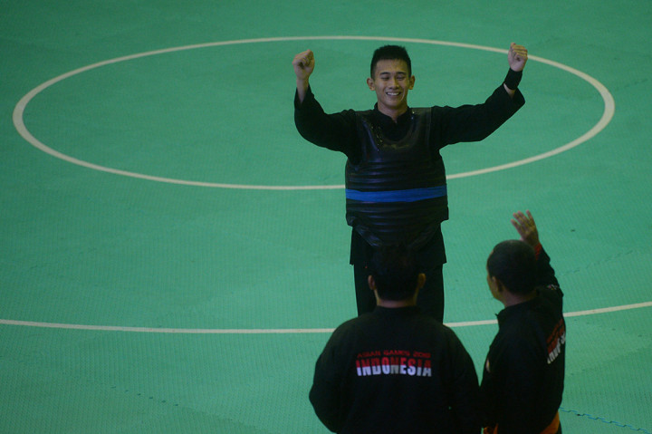 Pesilat Indonesia Iqbal Candra Pratama mengangkat tangannya usai mengalahkan pesilat Malaysia Razak Bin Ghazali dalam babak final 60-65 kg putra cabang Pencak Silat 18th Asian Games Invitation Tournament di JIExpo Kemayoran, Jakarta. ANTARA/Akbar Nugroho Gumay