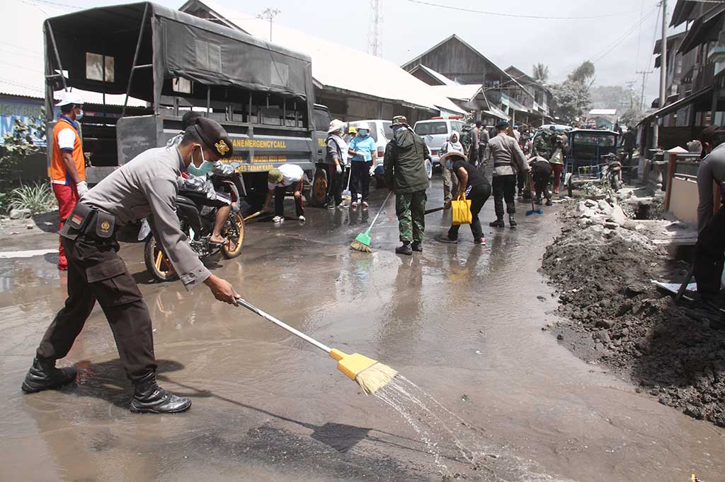 Prajurit TNI bersama Polri dan warga membersihkan jalan yang tertutup debu vulkanik erupsi Gunung Sinabung pascaerupsi, di Desa Payung, Karo, Sumatera Utara, Selasa, 20 Februari 2018. ANTARA/Ahmad Putra