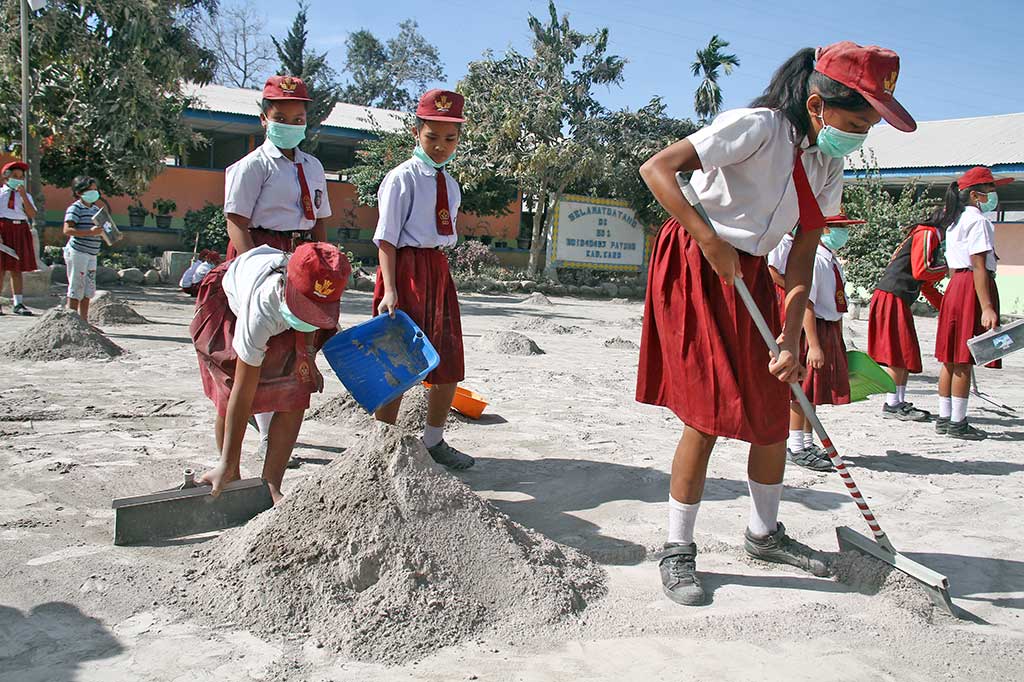 Sejumlah siswa SD membersihkana abu vulkanik yang memenuhi halaman sekolah mereka, pascaerupsi Gunung Sinabung, di Desa Payung, Karo. ANTARA/Ahmad Putra