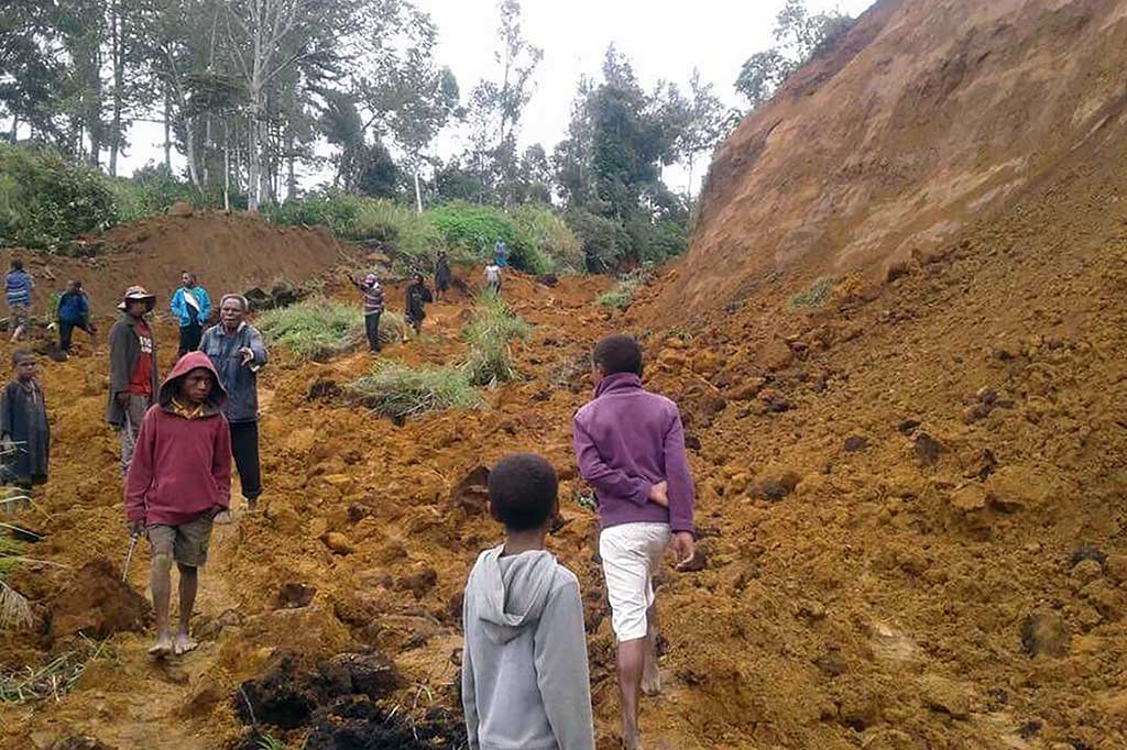 Warga berjalan di lokasi longsor di dekat Desa Ekari di wilayah dataran tinggi Papua Nugini setelah gempa berkekuatan 7.5 SR.