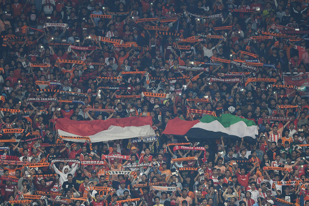Suporter membentangkan bendera dan syal dalam laga kedua Grup H Piala AFC antara Persija Jakarta melawan Tampines Rovers di Stadion Utama Gelora Bung Karno, Jakarta.

