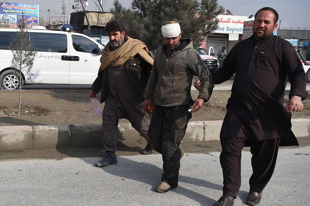 Warga membantu seorang pria yang terluka di dekat lokasi serangan bom mobil bunuh diri yang menargetkan tentara asing di Kabul, Jumat, 2 Maret 2018.
