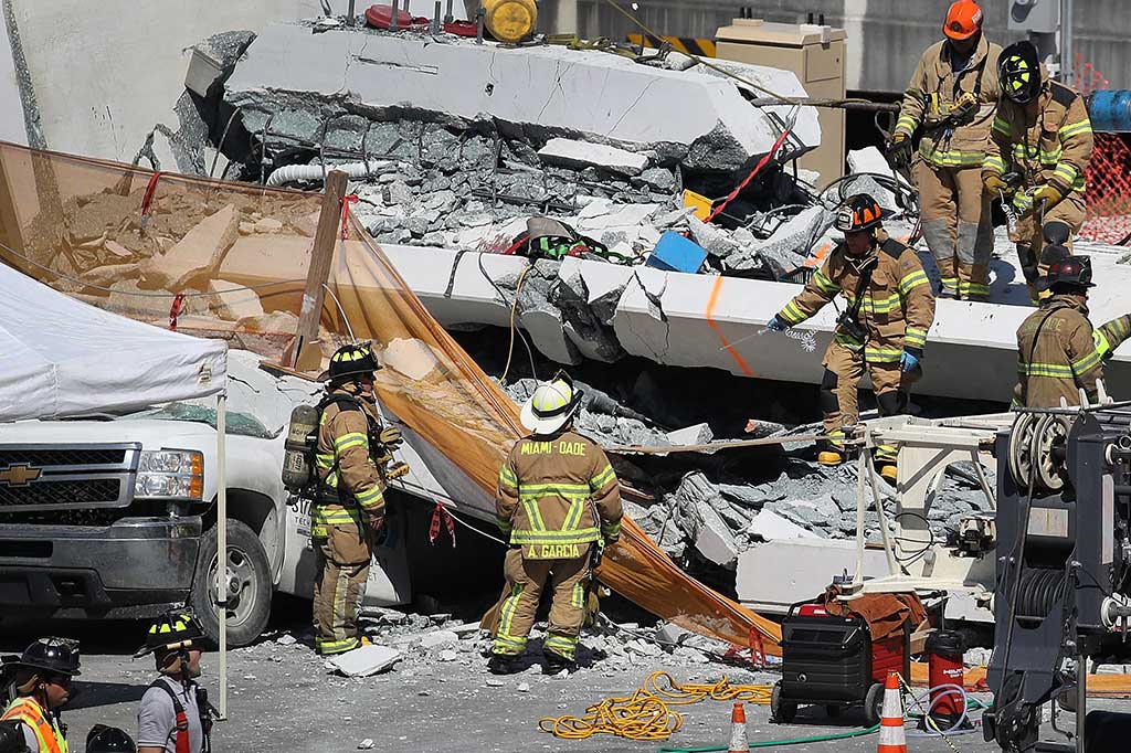 Petugas pemadam kebakaran Miami dan unit penyelamat lainnya berusaha mencari korban di bawah jembatan penyeberangan orang (JPO) yang runtuh di Miami, Florida, Kamis, 15 Maret 2018 waktu setempat. 