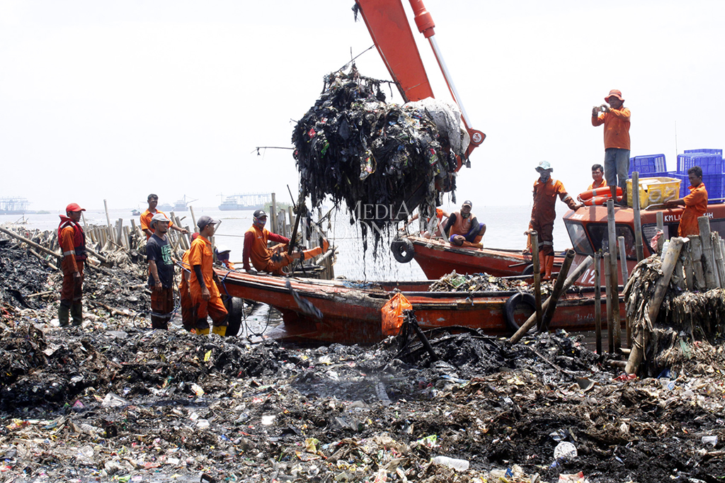 Petugas menggunakan alat berat membersihkan tumpukan sampah laut di wilayah konservasi hutan mangrove Muara Angke, Jakarta, Minggu (18/3).