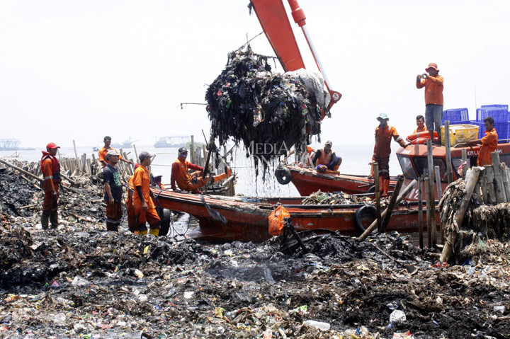 Petugas menggunakan alat berat membersihkan tumpukan sampah laut di wilayah konservasi hutan mangrove Muara Angke, Jakarta, Minggu (18/3).