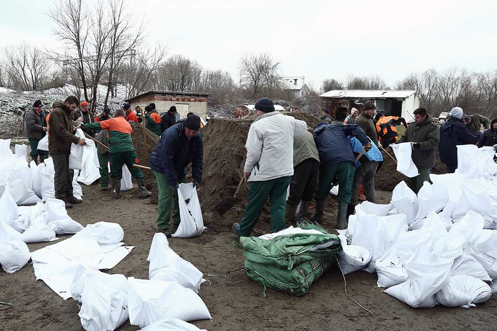 Tentara dibantu relawan mempersiapkan karung berisi pasir untuk membuat tanggul. Permukaan air naik 1 centimeter per jam dan diperkirakan mencapai puncaknya pada Selasa, 20 Maret 2018. Kenaikan permukaan air tertinggi sebelumnya tercatat 907 centimeter pada 1970 silam. 