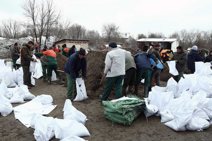 Tentara dibantu relawan mempersiapkan karung berisi pasir untuk membuat tanggul. Permukaan air naik 1 centimeter per jam dan diperkirakan mencapai puncaknya pada Selasa, 20 Maret 2018. Kenaikan permukaan air tertinggi sebelumnya tercatat 907 centimeter pada 1970 silam. 