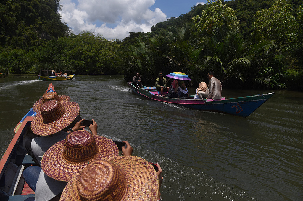 Wisatawan menaiki perahu wisata ketika berwisata di Kawasan karst Rammang-rammang, Maros, Sulawesi Selatan. Wisata tersebut merupakan salah satu wisata populer di Sulawesi Selatan yang menawarkan keindahan alam dengan batuan karst. 