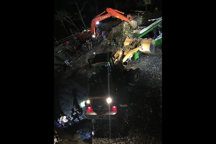 Para petugas penyelamat menuruni jurang untuk mengeluarkan para penumpang dari dalam bus yang berada di antara pepohonan dan semak, sekitar 15 meter dari atas jalanan.