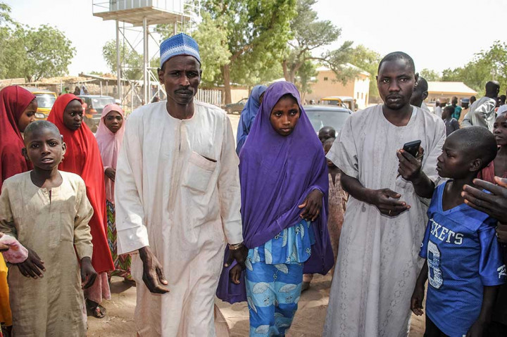 Seorang gadis yang dibebaskan oleh Boko Haram berjalan bersama ayahnya (kiri) di Dapchi, Nigeria, pada 21 Maret 2018. Boko Haram membebaskan 104 dari 110 siswi yang diculik di Dapchi, timur laut Nigeria, sebulan lalu. 