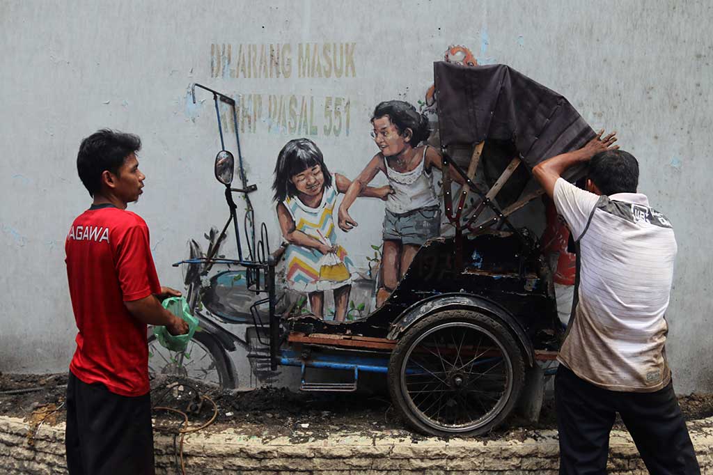 Pekerja memasang kerangka becak yang digabungkan ke mural karya pelukis jalanan dunia Ernest Zacharevic yang sempat hilang di Jalan Perdana, Medan, Sumatera Utara, Kamis, 22 Maret 2018.