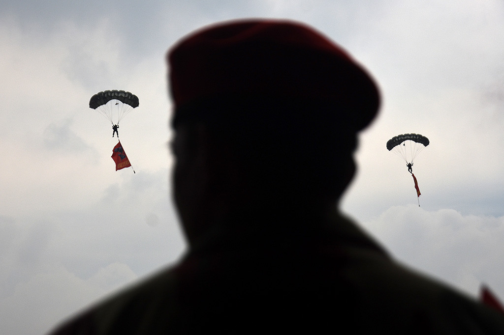 Pasukan penerjun Kopassus melakukan aksi terjun payung sambil membawa bendera kesatuannya.
