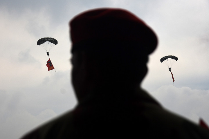 Pasukan penerjun Kopassus melakukan aksi terjun payung sambil membawa bendera kesatuannya.
