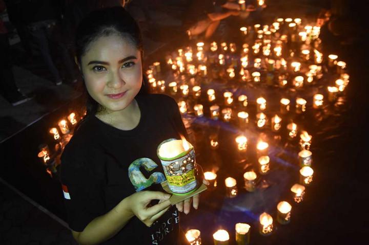 Seorang duta 'Earth Hour' Surabaya membawa lilin ketika memperingati 'Earth Hour 2018' di Surabaya, Jawa Tiimur, Sabtu' 24 Maret 2018 malam. ANTARA/M Risyal Hidayat