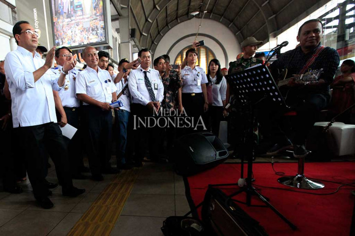Budi Karya terlihat mengikuti irama lagu yang diainkan sebuah band yang sedang mengiringi musik di tengah keramaian Stasiun Jakarta Kota.
