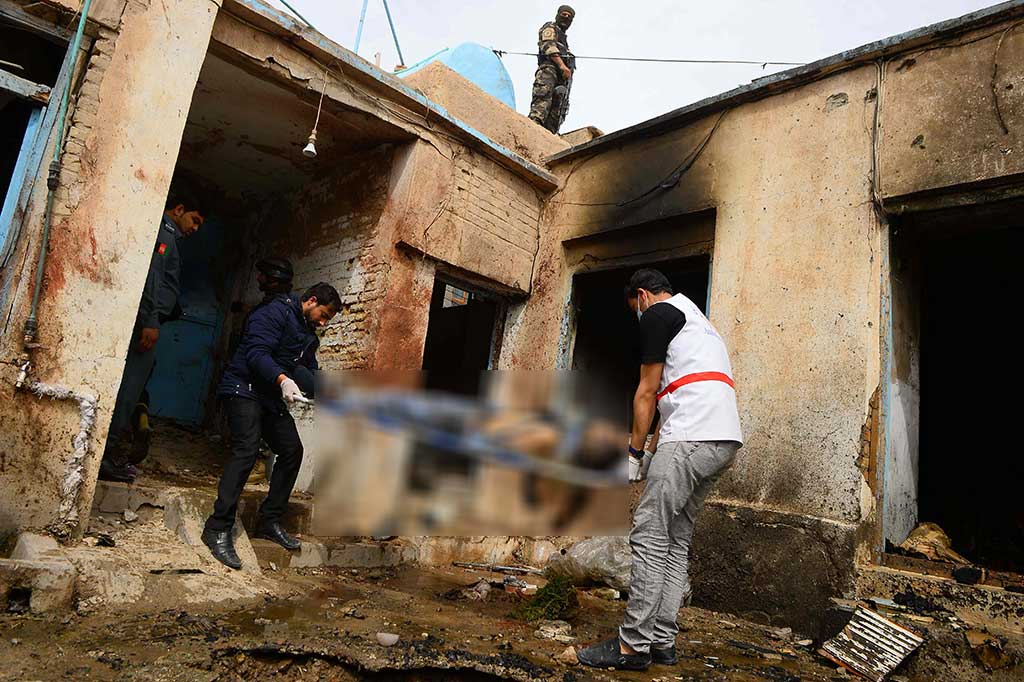 Sukarelawan dan petugas keamanan Afghanistan mengevakuasi jenazah seorang pria setelah dua pembom bunuh diri menyerang sebuah masjid Syiah di Herat pada 25 Maret 2018. Ledakan terjadi pada Minggu siang, setelah dua pembom bunuh diri berusaha memasuki Masjid Nabi-e-Akram di Permukiman Chahr Su.
