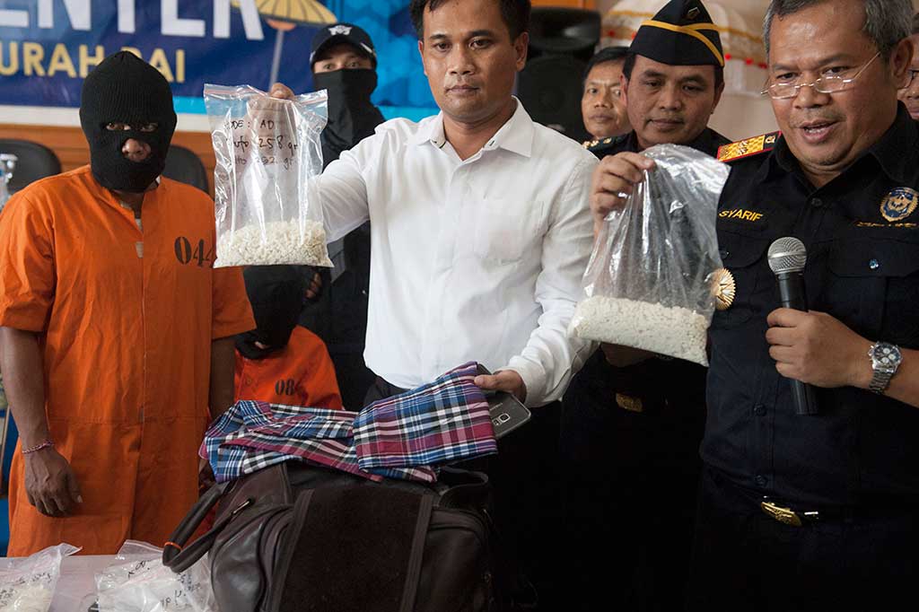 Kepala Direktorat Jenderal Bea Cukai Bali, NTB dan NTT Syarif Hidayat (kanan) dan polisi memperlihatkan barang bukti kokain yang dibawa tersangka INA (kiri) dalam konferensi pers di Kantor Bea Cukai Ngurah Rai, Denpasar, Senin, 26 Maret 2018. ANTARA/Nyoman Budhiana