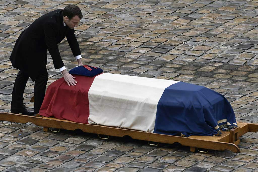 Presiden Prancis Emmanuel Macron menempatkan tangannya di peti mati Letnan Kolonel Arnaud Beltrame setelah memberikan anumerta dengan Legiun Kehormatan dalam sebuah upacara nasional di Paris, Rabu, 28 Maret 2018 waktu setempat. AFP/Philippe Lopez