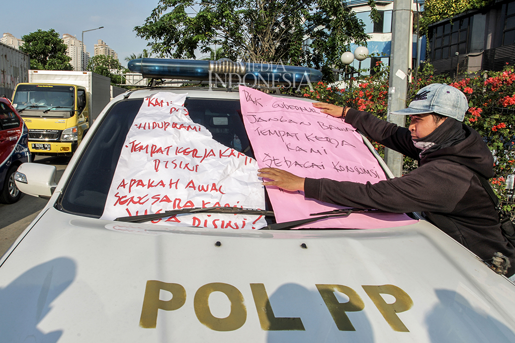 Tak mau kalah, karyawan Alexis yang berunjuk rasa menempelkan karton di mobil Satpol PP yang terparkir di luar gedung.