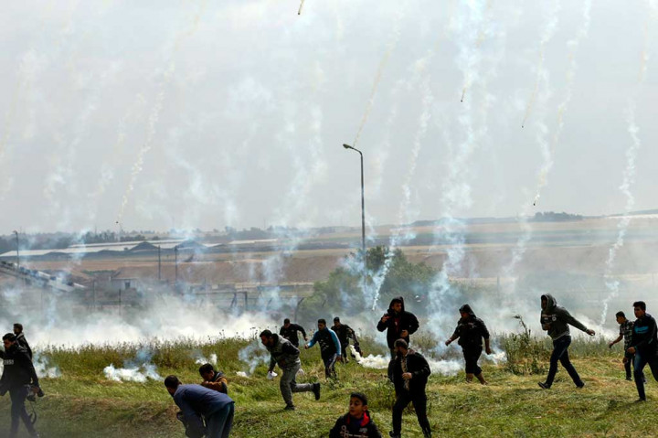 Warga Palestina berlarian menghindari tembakan gas air mata yang dilontarkan militer Israel.