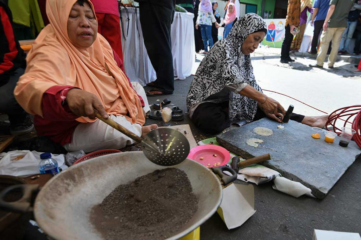 Warga memasak biji melinjo untuk dijadikan emping dengan menggunakan pasir saat Festival Condet Punye Potensi di kawasan Condet, Bale Kambang, Jakarta, Sabtu, 31 Maret 2018. 
