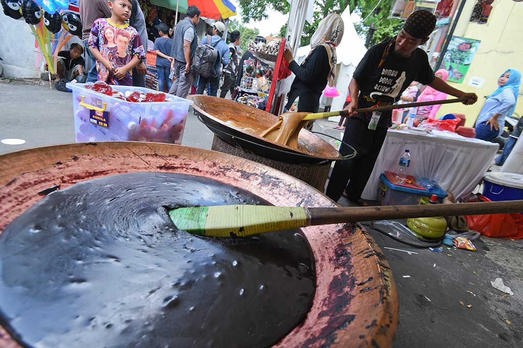 Perajin mengaduk dodol yang merupakan salah satu makanan khas Betawi.