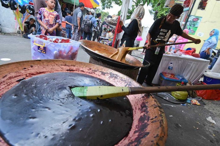 Perajin mengaduk dodol yang merupakan salah satu makanan khas Betawi.