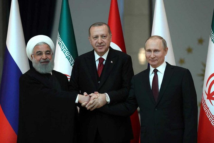 Presiden Iran Hassan Rouhani, Presiden Turki Tayyip Erdogan, dan Presiden Rusia Vladimir Putin berjabat tangan bersama selama konferensi pers usai melakukan pertemuan tripartit untuk membahas perdamaian Suriah, di Ankara, Rabu, 4 April, 2018.