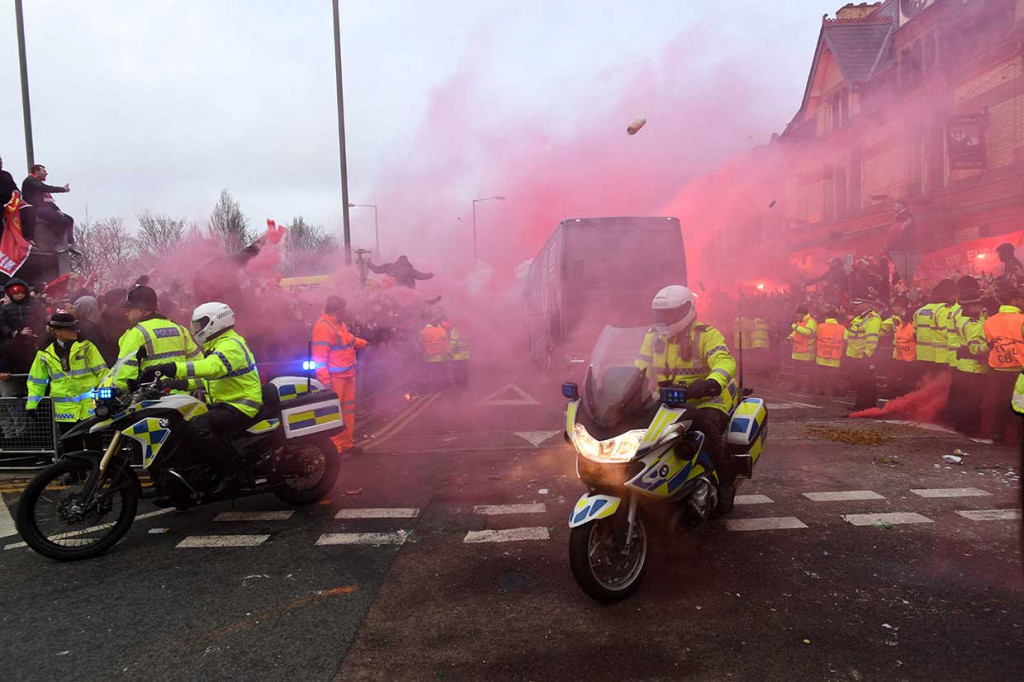 Para suporter juga menyalakan flare sembari menyanyikan lagu-lagu klub kesayangan mereka saat bus tim City tiba di Anfield.