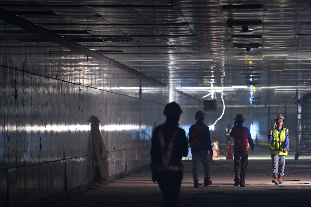Pekerja melintasi lorong proyek pembangunan Stasiun MRT Bundaraan HI, Jakarta.