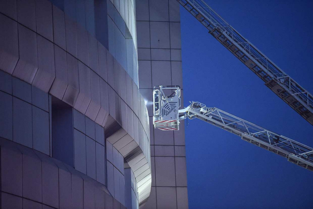 Petugas pemadam kebakaran menggunakan lift elevasi untuk memadamkan api di bagian atas gedung rumah sakit. 