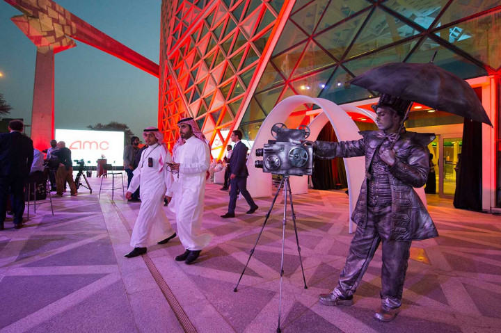 Aktor pantomim berdiri di belakang model kamera bioskop vintage di pintu masuk bioskop AMC di Riyadh, menjelang pemutaran film uji pertama dalam lebih dari tiga dekade terakhir. AFP/Saudi Royal Palace/Bandar Al-Jaloud