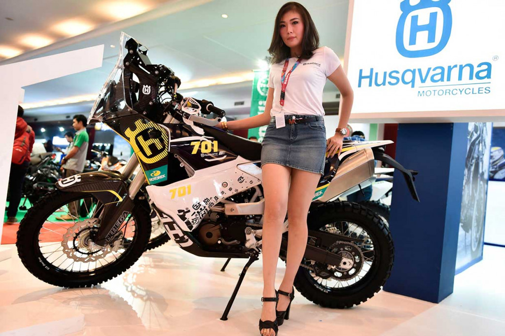 Seorang model berpose di depan motor trail Husqvarna. 