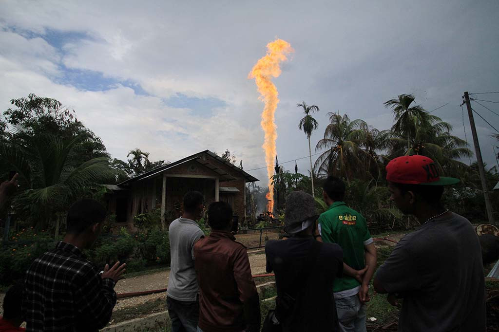 Warga menyaksikan semburan api di lokasi pengeboran minyak illegal yang dikelola warga di kawasan Dusun Kamar Dingin Desa Pasir Putih, Ranto Panjang Peureulak, Kabupaten Aceh Timur, Aceh. ANTARA/Rahmad