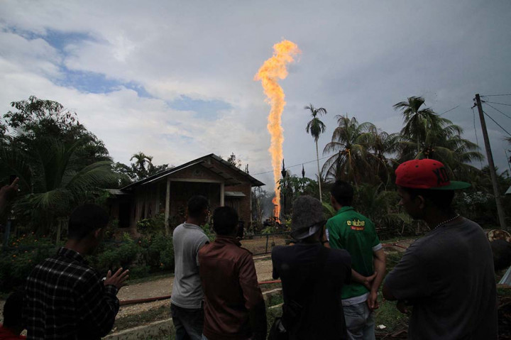 Warga menyaksikan semburan api di lokasi pengeboran minyak illegal yang dikelola warga di kawasan Dusun Kamar Dingin Desa Pasir Putih, Ranto Panjang Peureulak, Kabupaten Aceh Timur, Aceh. ANTARA/Rahmad