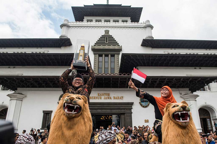 Gubernur Jawa Barat Ahmad Heryawandidampingi istri Netty Prasetiyani Heryawan membawa Piala Parasamya Purnakarya Nugraha saat diarak keliling Gedung Sate, Bandung, Jawa Barat, Kamis, 26 April 2018.