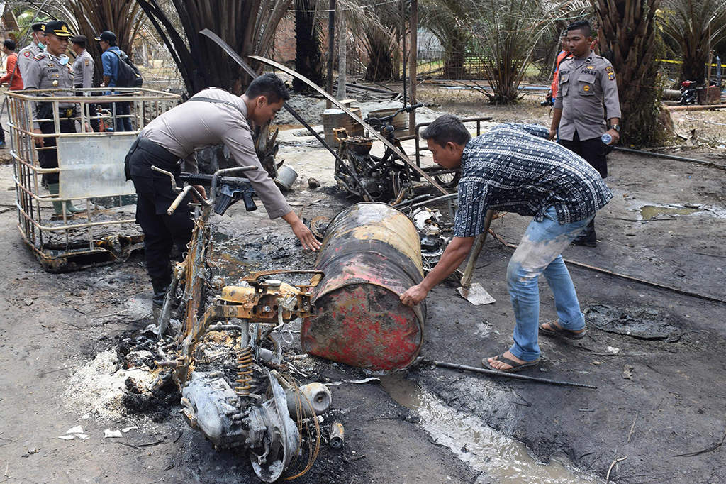 Pendinginan area ledakan dan rumah warga sekitar titik semburan api itu untuk meredam suhu panas dan meminimalisir endapan minyak serta gas yang dapat memicu kobaran api, sekaligus upaya pencarian korban yang tertimbun material pengoboran. AFP/ ILYAS ISMAIL