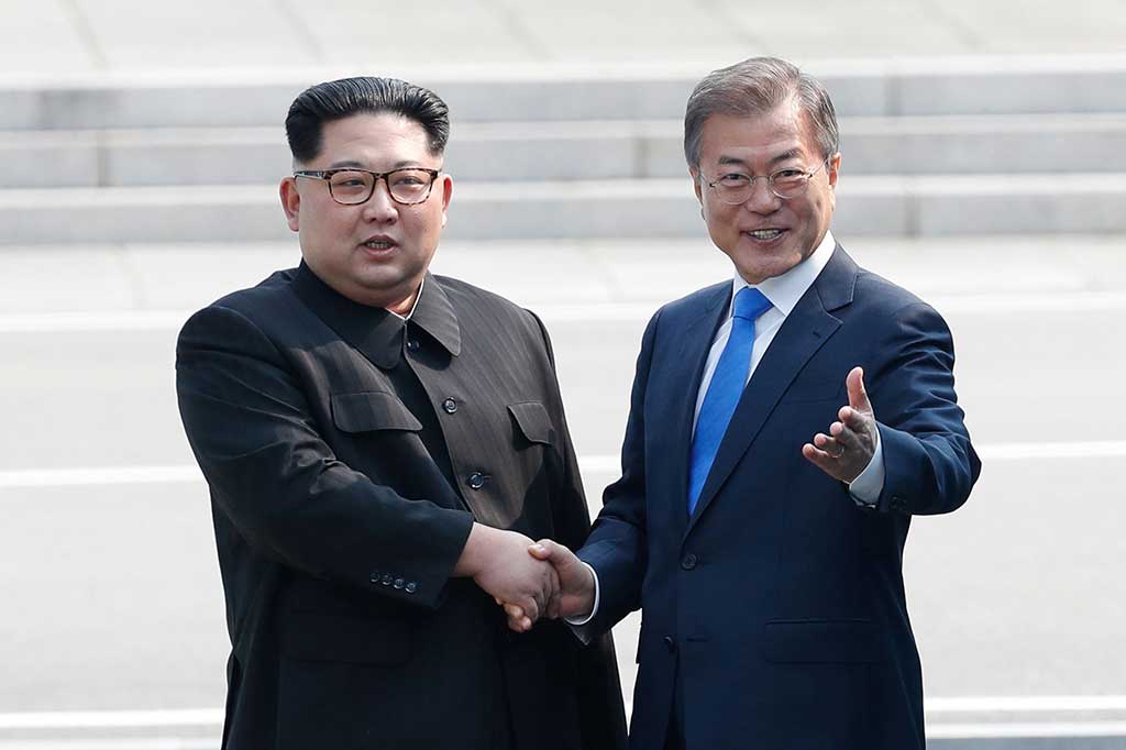 Presiden Korsel Moon Jae-in berjabat tangan dengan pemimpin tertinggi Korut Kim Jong Un di Zona Demiliterisasi yang membagi kedua negara, Jumat, 27 April 2018. 