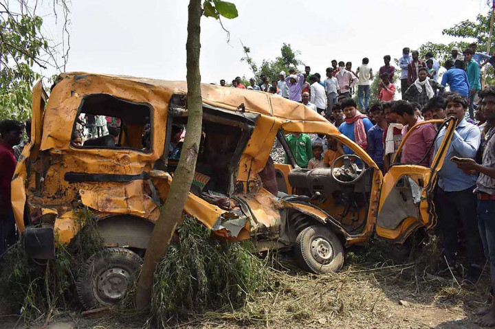 Warga berkerumun di dekat bus sekolah yang ringsek setelah dihantam sebuah kereta di Distrik Kushinagar, Negara Bagian Uttar Pradesh, India, Kamis 26 April 2018.