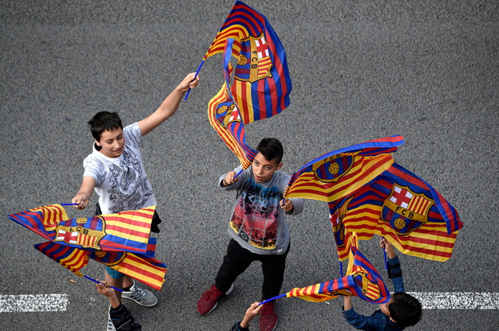 Suporter Barcelona mengibarkan bendera saat bus yang ditumpangi Lionel Messi dan kawan-kawan melintas. 