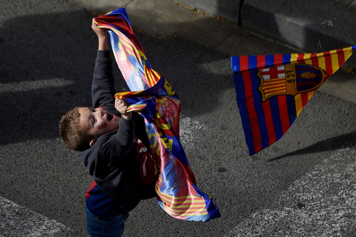 Suporter cilik Barcelona mengibarkan bendera saat bus yang ditumpangi Lionel Messi dan kawan-kawan melintas. 