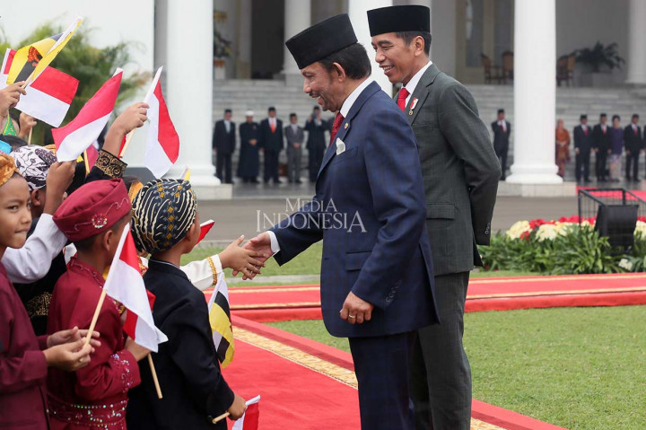 Sultan Brunei disaksikan Presiden Jokowi menyalami sejumlah anak yang mengenakan pakaian daerah.