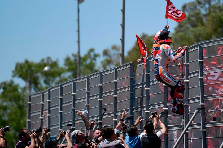 Marquez menaiki pagar penonton untuk menyapa penggemarnya setelah memenangi Moto-GP Spanyol.